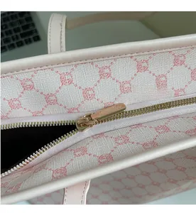 Close-up of smooth gold-tone zipper and pink leather puller on floral tote bag