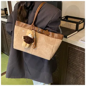 Detail of vintage two-tone tote bag with brown leather strap and cute bear charm