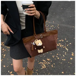 Detail of brown suede patchwork underarm bag with cute teddy bear charm and metal buckle