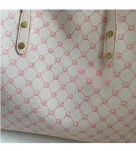 Close-up of soft floral canvas texture and leather handle with golden rivets
