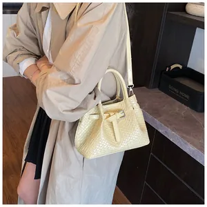 Close-up of cream woven bucket bag with elegant handle and adjustable shoulder strap