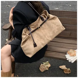 Detail of vintage suede tote bag with leather straps and metal buckle in autumn park