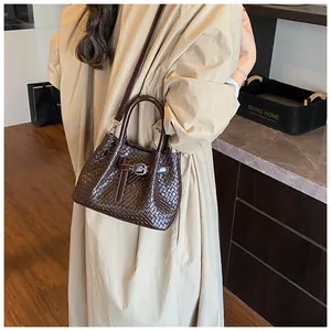 Detail of dark brown woven textured handbag with buckle strap and dual top handles