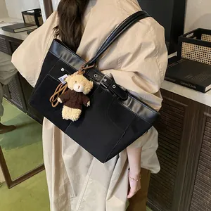 Minimalist black tote bag with brown plush bear charm for stylish office commuting