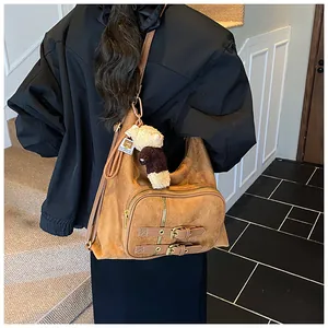 Bolso bandolera vintage marrón de ante con cremalleras, hebillas y un colgante de osito