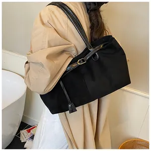 Side view of model wearing a large black vintage tote bag with gold metal buckle detail