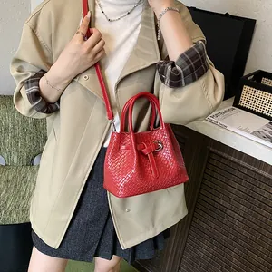 Red woven leather handbag with dual handles and crossbody strap in a stylish tote design