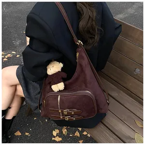 Primer plano del bolso hobo de gamuza marrón con un bonito colgante de oso de peluche