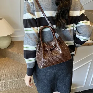 Fashionable dark brown woven handbag with crossbody strap in a cozy indoor setting
