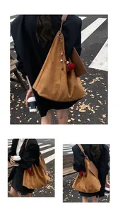 Detail einer braunen Wildleder-Hobo-Tasche mit Vintage-Anhängern auf der Straße