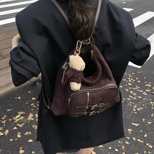 Mochila de ante marrón oscuro con hebillas y colgante de osito en un estilo vintage