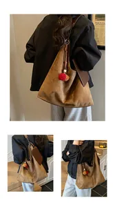 Detail der karamellbraunen Wildleder-Tragetasche mit Plüschbommeln und kleiner Tasche