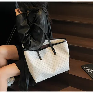 Detail of a large capacity tote bag featuring beige geometric patterns and black straps