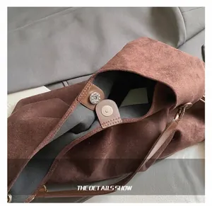 Detailansicht der braunen Wildledertasche mit Magnetverschluss aus Metall und feinen Nähten