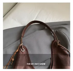Detail einer braunen Wildledertasche mit Metallschnalle und gewebtem Quasten-Akzent