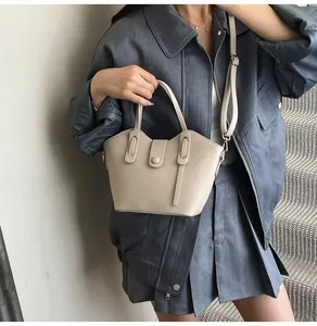 Mannequin portant un sac seau beige chic avec poignées et bandoulière réglable