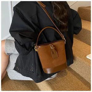 Detailed close-up of brown suede and smooth leather patchwork bucket bag with gold hardware