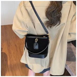 Detail of retro black bucket bag with smooth leather trim and golden metal clasp