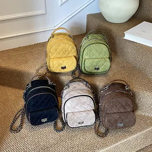 Mini zaini trapuntati in cinque colori vivaci esposti su una scala in tessuto