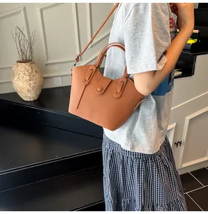 Détail du sac seau en cuir caramel avec bord ondulé et fine bandoulière amovible
