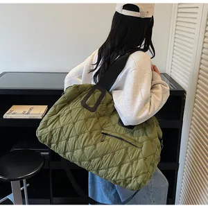 Detailed side view of an olive green quilted puffer tote bag with wide black strap