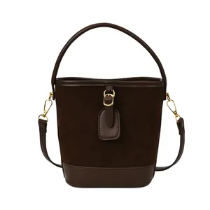 Brown suede bucket bag with leather trim and gold hardware in a frontal studio view