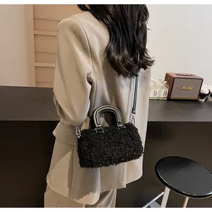 Dettaglio della borsa a cuscino in pile nero con manici in pelle liscia e tracolla fine