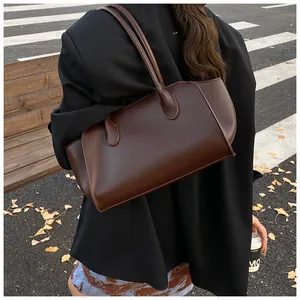 Detail einer dunkelbraunen Leder-Shopper-Tasche, getragen von einem Model im Freien