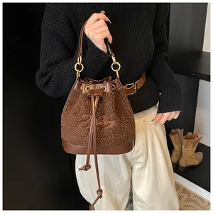 Detail of brown lamb wool bucket bag with leather base, drawstring, and embroidery