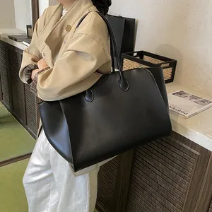Minimalistische große schwarze Tragetasche für Damen am Modell in einem stilvollen Raum