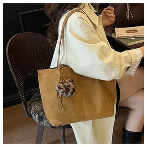 Detail of large brown suede tote bag with leopard heart charm and leather tassels