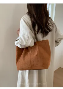 Detailed view of large brown suede tote bag with minimalist vertical stitching and slim straps