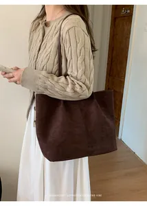 Deep brown oversized tote bag in faux suede fabric worn by a model in a minimalist setting