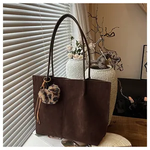 Close-up of a large brown suede tote bag featuring a trendy leopard print pompom detail