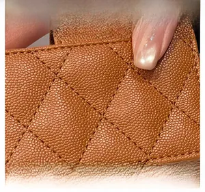 Macro view of brown PU leather with caviar texture and quilted diamond stitching on wallet