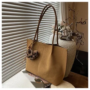 Detail of tan suede tote bag with decorative stitching and leopard heart charm