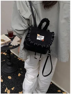 Detailed close-up of a black drawstring backpack with ruffle edges and cute bear charms