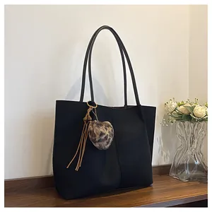 Detail of black tote bag with heart leopard plush charm and brown tassel accessory