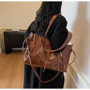 Detailed view of brown vintage tote bag with fringe tassels and woven leather strap detail