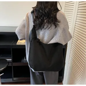 Primer plano del gran bolso hobo negro con correa ajustable y diseño minimalista