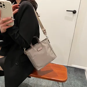 Minimalist nylon tote bag with leather handles and wide adjustable strap in khaki gray