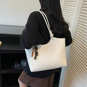 Minimalist cream white leather tote bag with shoulder strap in a stylish home setting