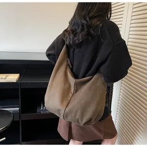 Detalle de un bolso hobo grande de ante marrón llevado en la espalda para estilo diario
