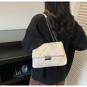 Detail showing beige quilted chain bag with silver clasp on a model's shoulder