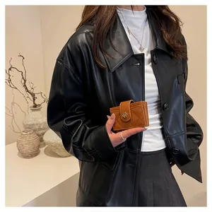 Detail of a brown quilted leather wallet with a golden floral buckle held by a model