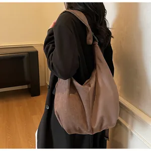 Detalle del bolso bandolera de ante marrón oscuro con correa ajustable y forma de media luna