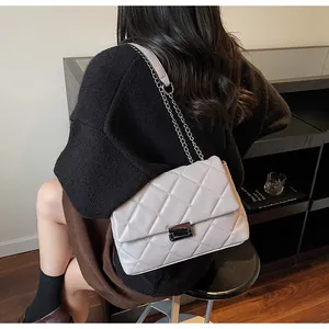 Detail shot of light grey quilted crossbody bag with silver chain strap on model