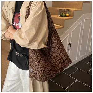 Detail view of leopard print tote bag fabric with fashion label and wide shoulder strap
