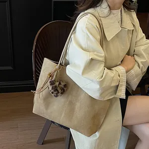Minimalist beige suede tote bag with leopard heart charm in a soft indoor setting