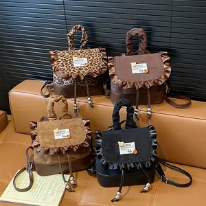 Mini leopard print backpack with ruffle trim in four colors on a leather bench